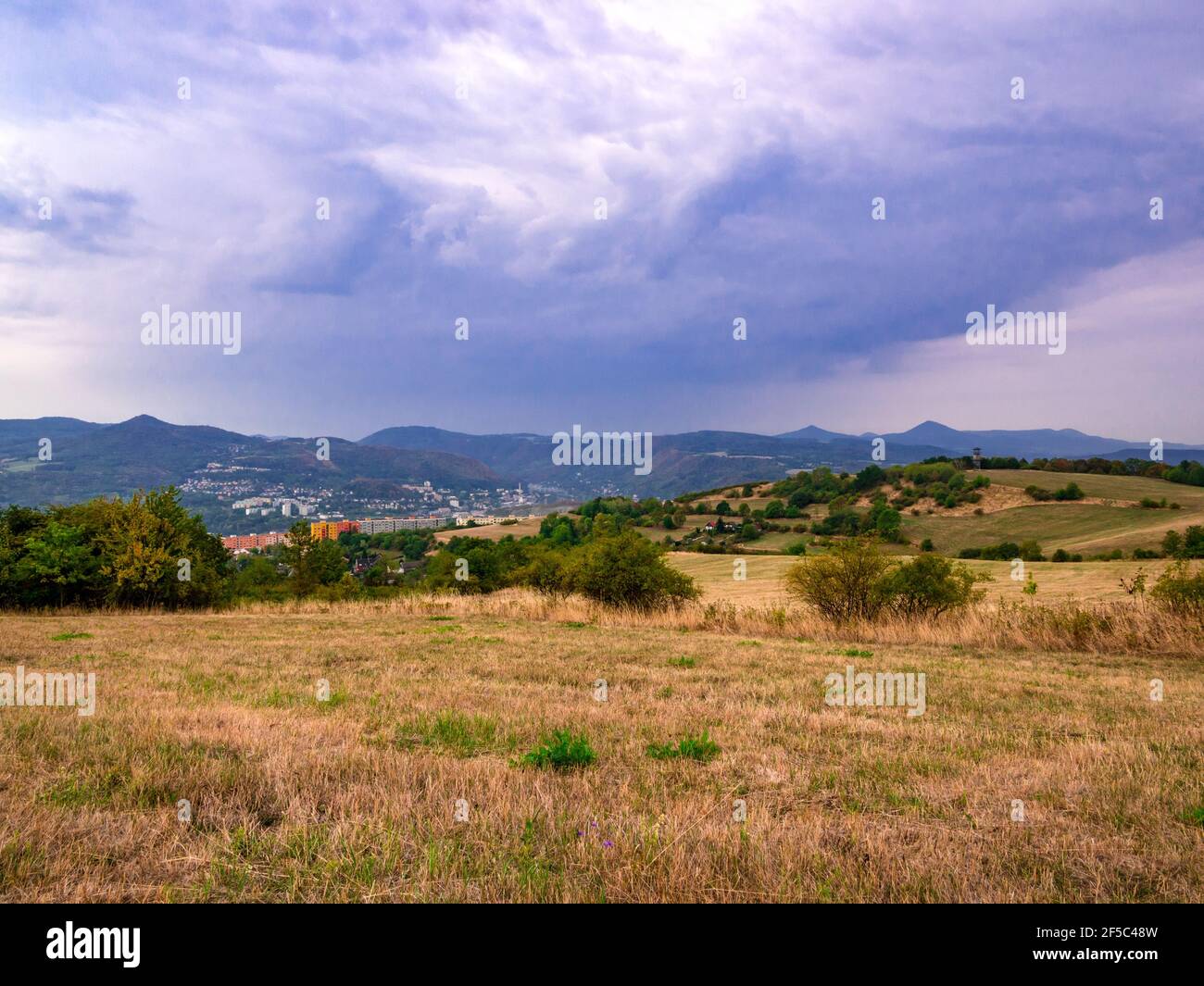 Massive dark heavy rain clouds over a hilly landscape with a town in ...