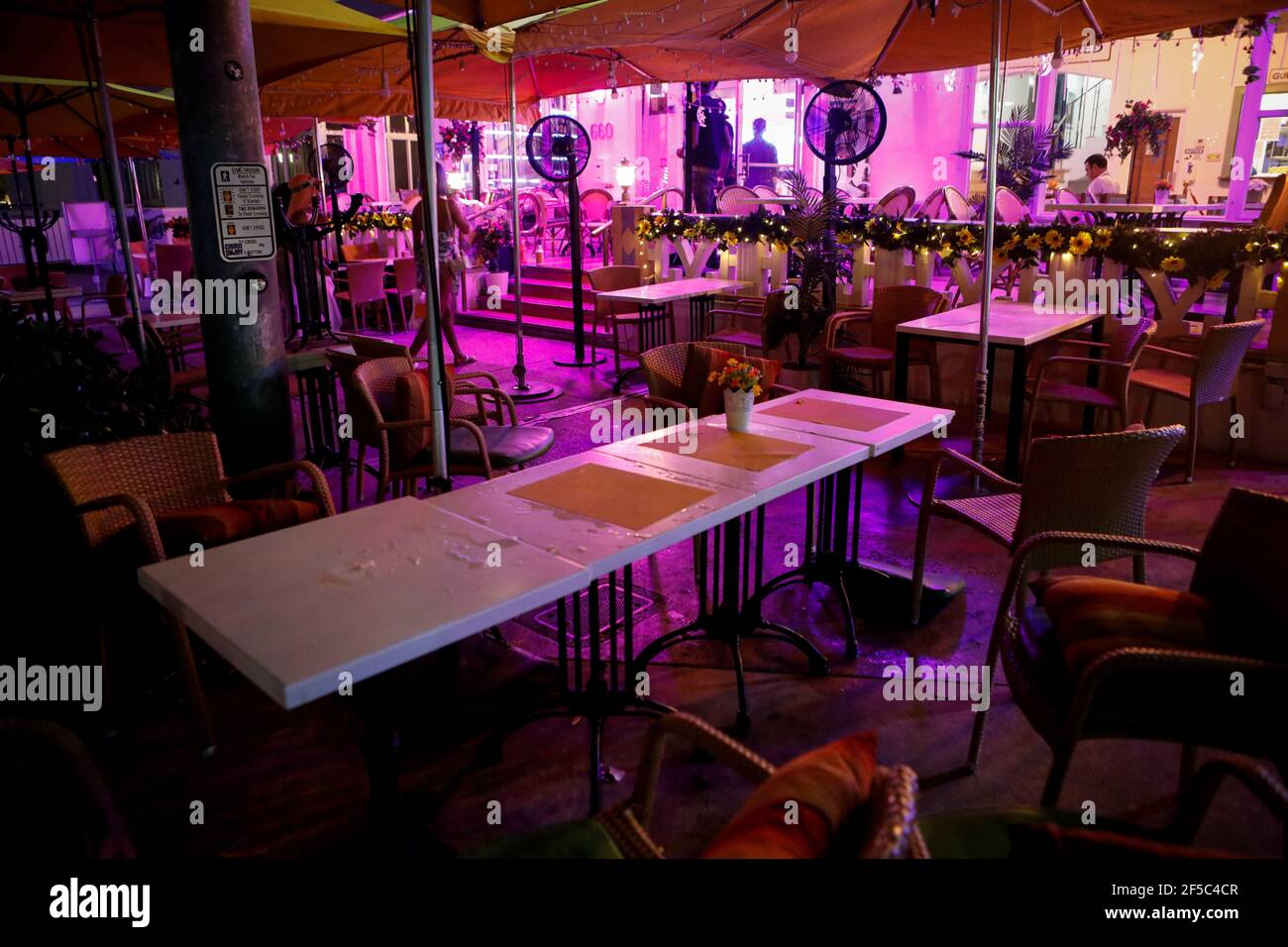 Empty tables are seen in a restaurant at Ocean Dr as Miami Beach police officers enforce an 8pm curfew imposed by local authorities on spring break festivities, amid the coronavirus disease (COVID-19) pandemic, in Miami Beach, Florida, U.S., March 25, 2021. REUTERS/Marco Bello Stock Photo