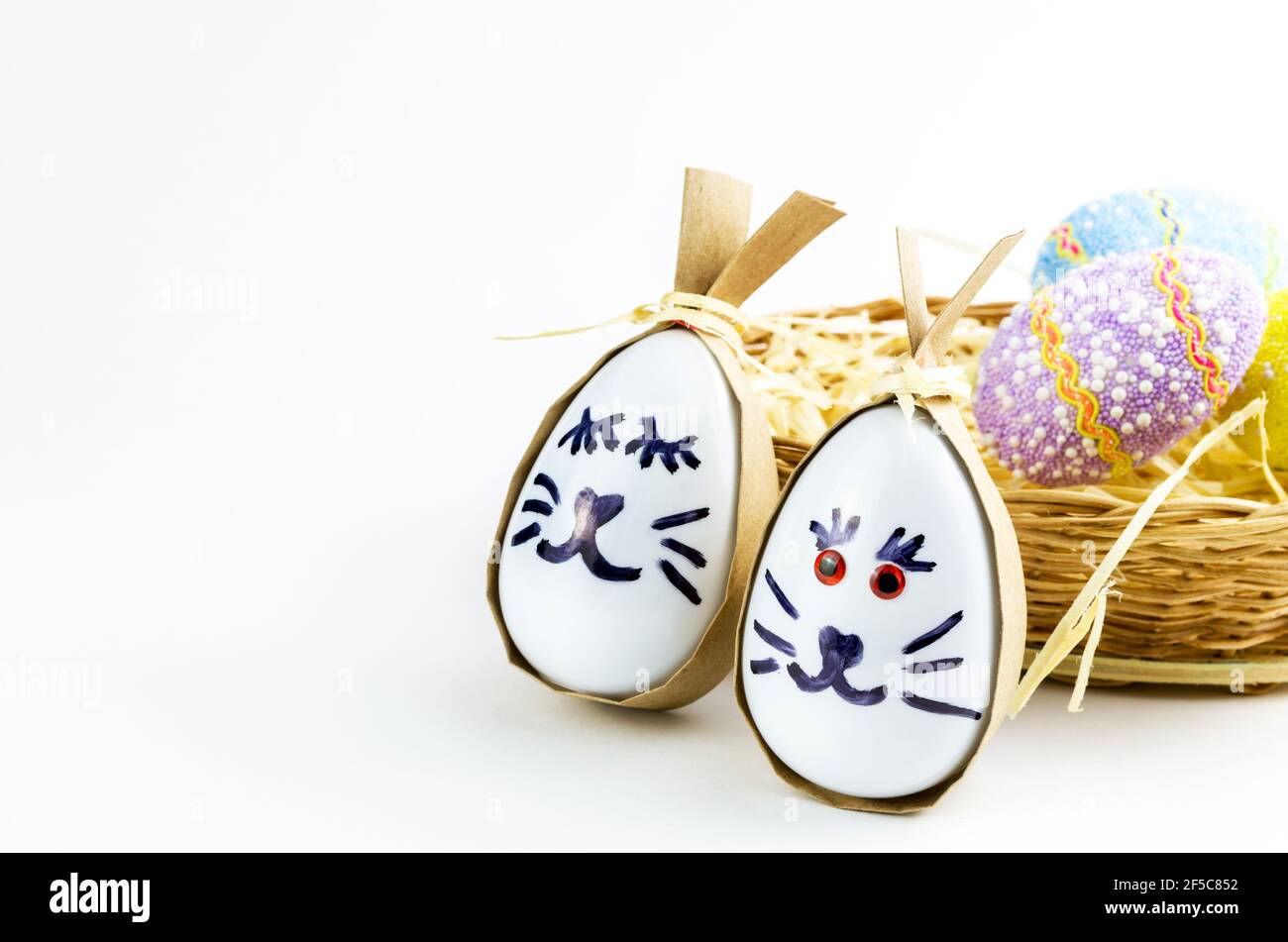 Happy easter bunny egg and eggs colored eggs  in a basket isolated on a trendy white background. Minimal easter concept. Easter card with copy space f Stock Photo