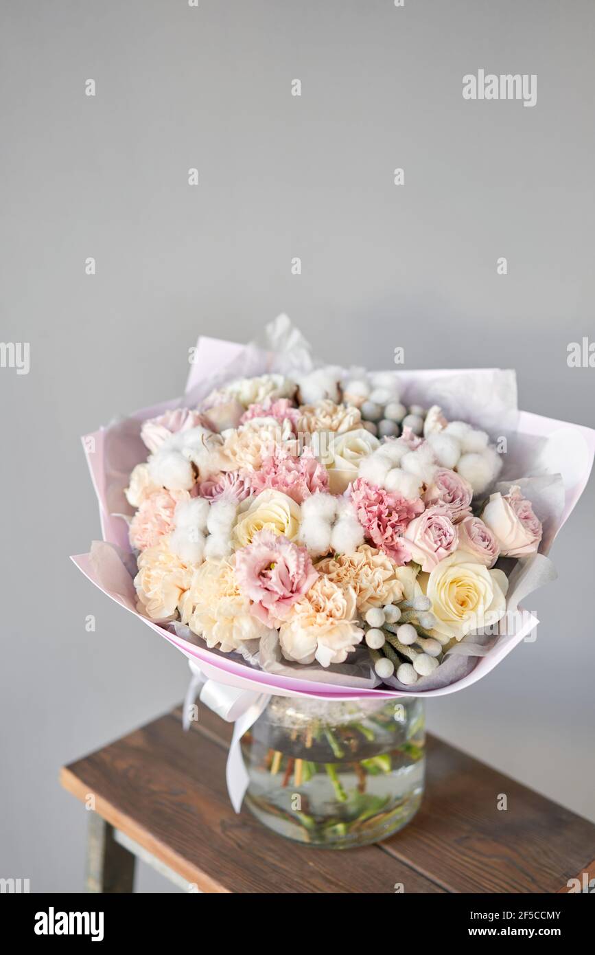 Beautiful bouquet of mixed flowers on wooden table. the work of the florist at a flower shop. Delivery fresh cut flower. European floral shop. Stock Photo