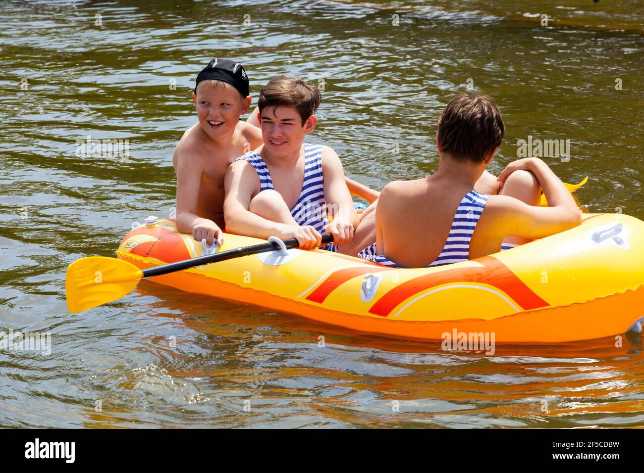 Three kids in inflatable boat, children enjoying summer adventures on water Stock Photo