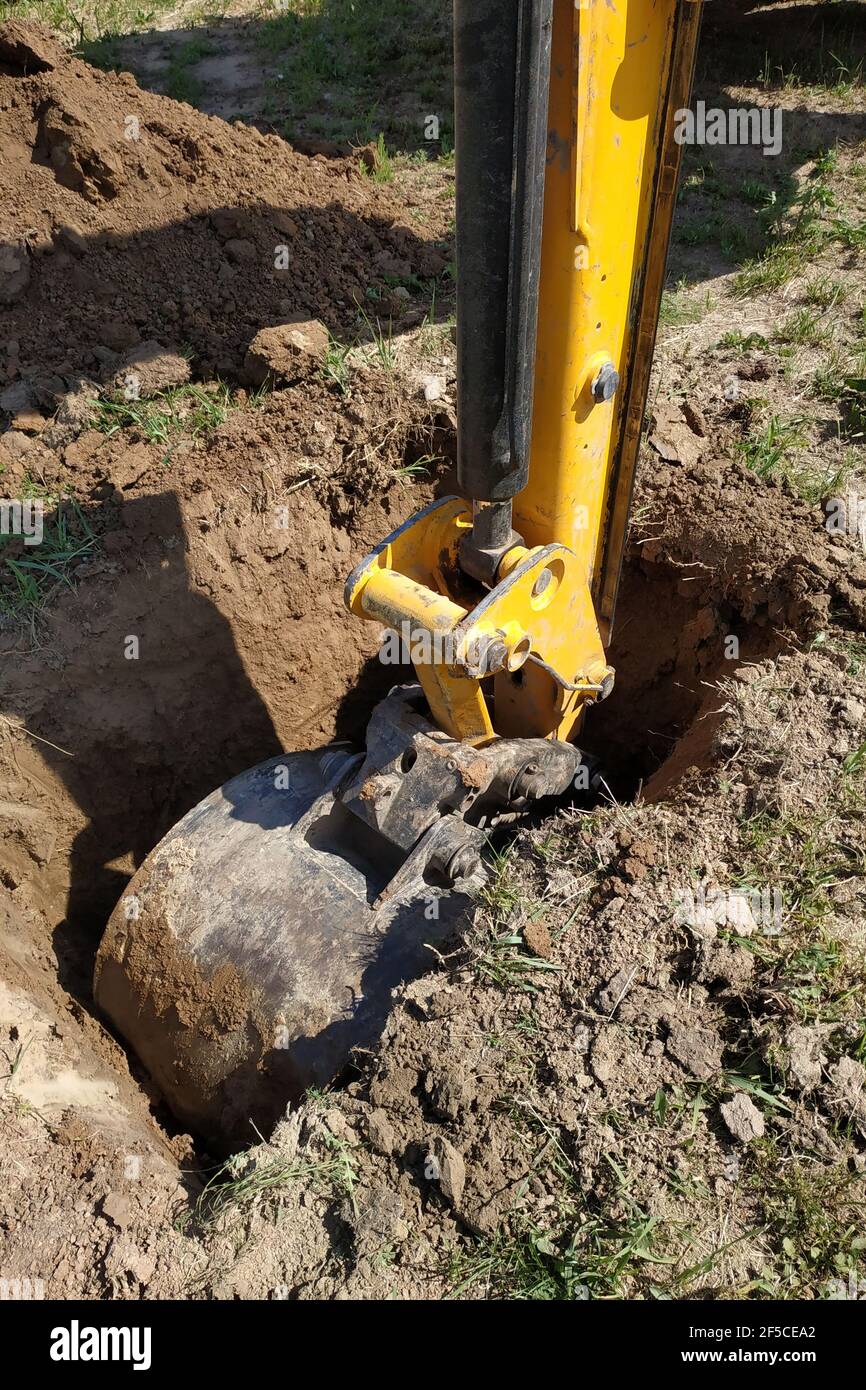 The yellow excavator digs a trench, construction works by means of ...
