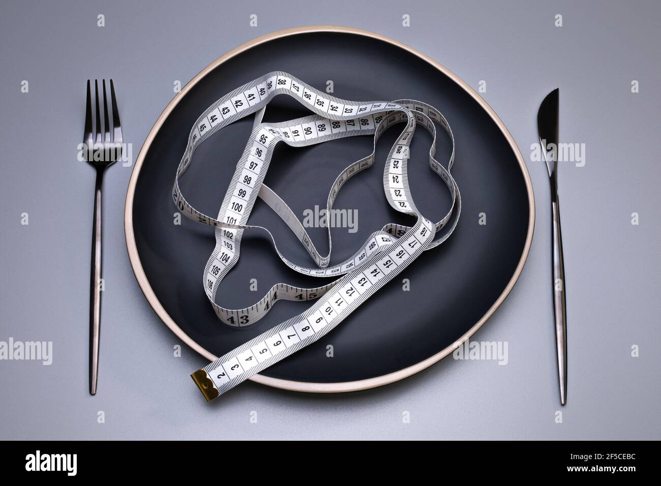 Measuring tape on the plate. Proper nutrition. Medical starvation. Diet for weight loss concept. Stock Photo