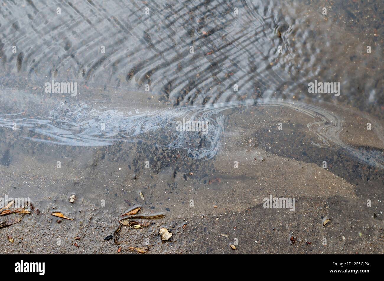 Stream of rainwater and oil products on the asphalt. Waste from the oil ...