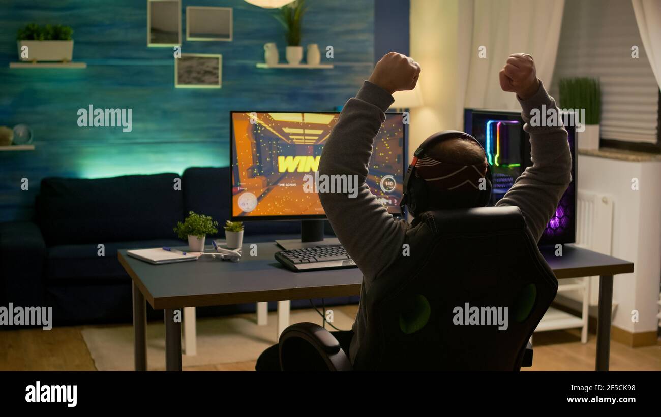 Videogamer player raising hands after winning first person shooter ...