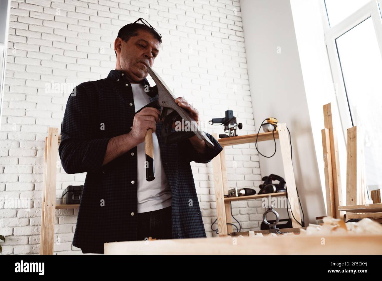 Carpenter's hands planing a plank of wood with a hand plane Stock Photo