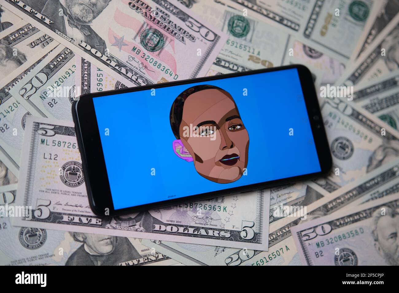 NFT self-portrait by Sophia the Robot. Self portrait by robot Sophia sold as NFT token seen on the smartphone which is placed on dollar banknotes. Con Stock Photo