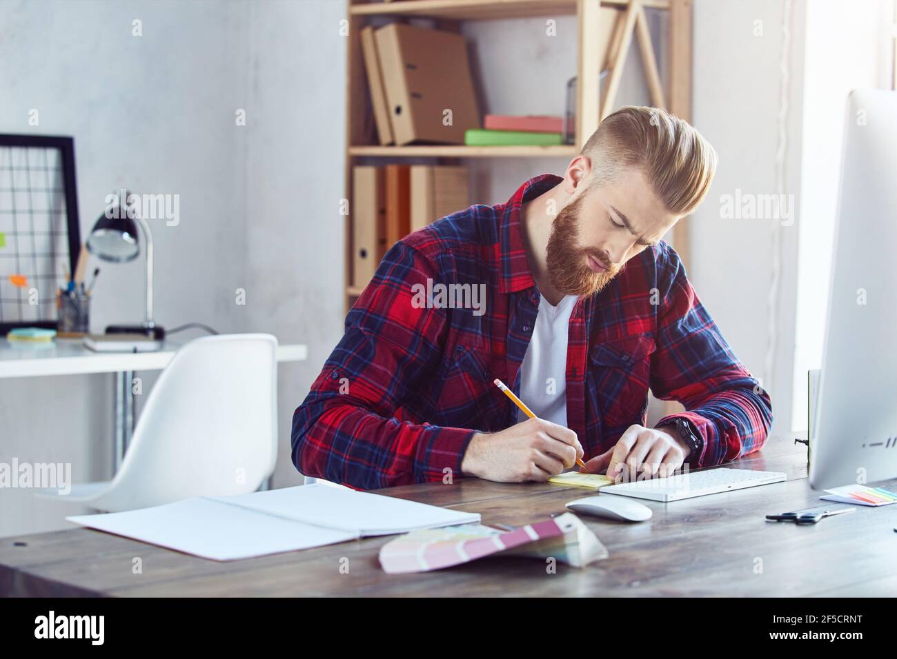 Stylish guy working at his workplace while writing notes on paper Stock ...