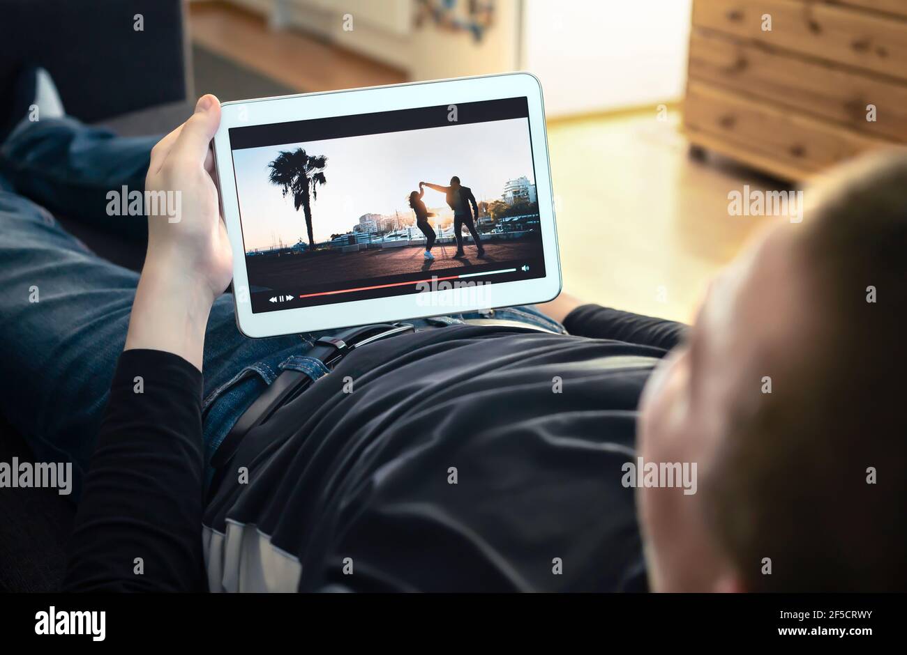 Watching VOD service and online movie stream. On demand film streaming, tv series or music video in smart device screen. Man enjoying entertainment. Stock Photo