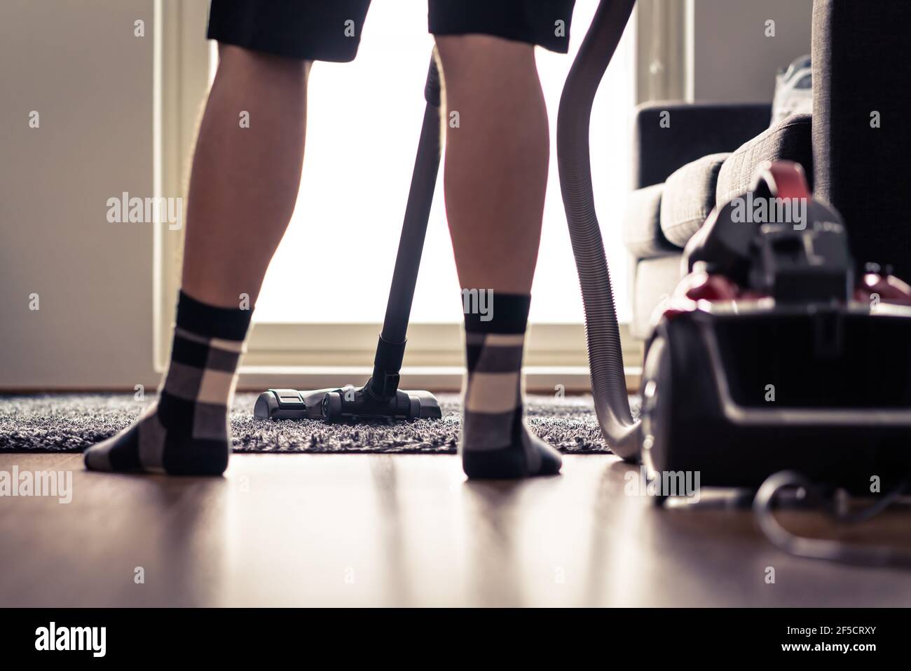 Vacuum cleaner. Man cleaning carpet and floor at home. Happy person