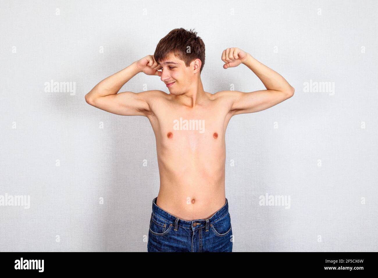 Skinny Young Man Muscle Flexing on the White Wall Background Stock Photo -  Alamy
