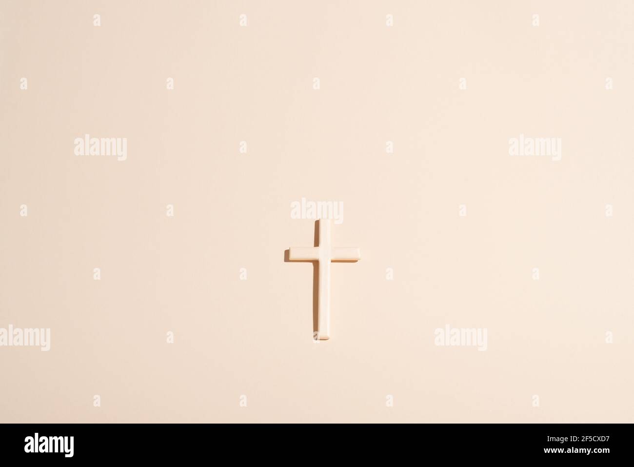 Cross or crucifix on light beige background. Clean simplistic design. Flat lay. Copy space. Stock Photo