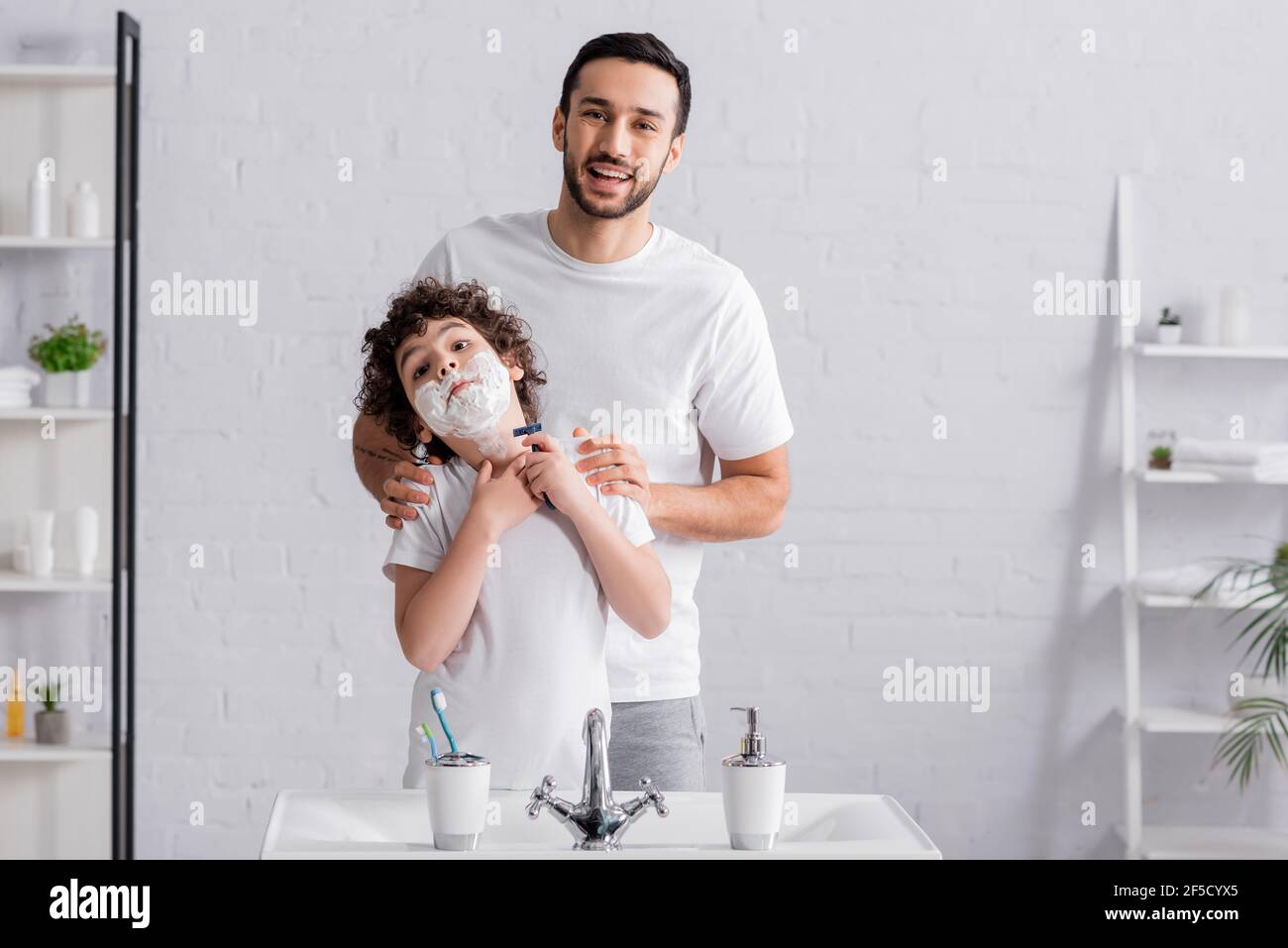 Boy in shaving foam holding razor near smiling father Stock Photo - Alamy