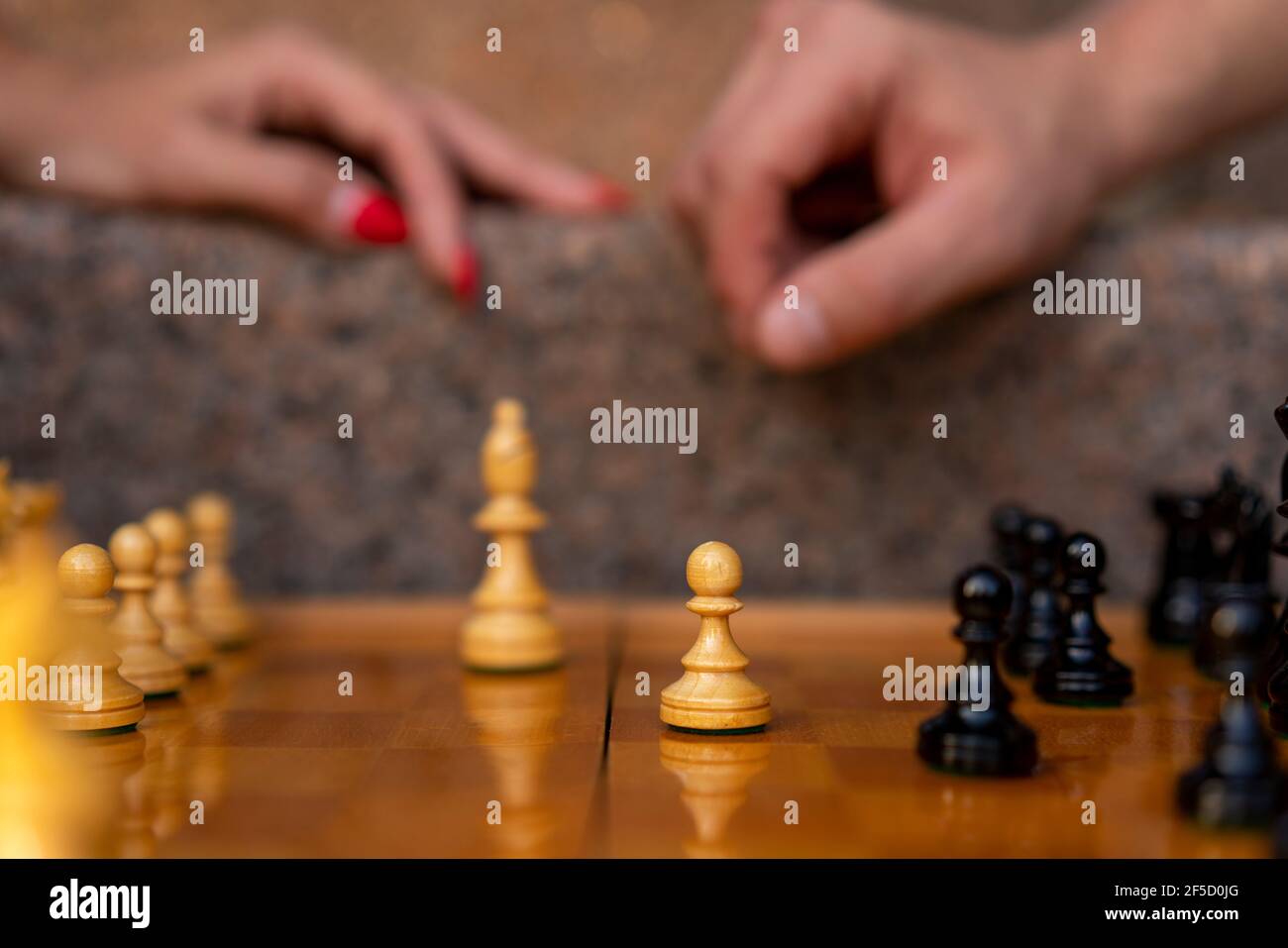 Chess board with figures on a sunny day in the park with bokeh and blurred background by a pair of female and male hands Stock Photo
