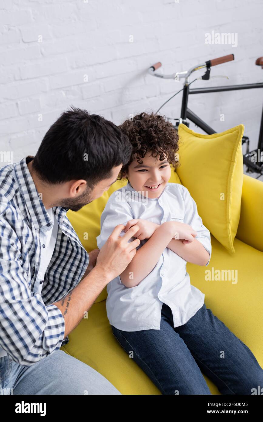 young arabian man tickling cheerful son while having fun at home Stock Photo
