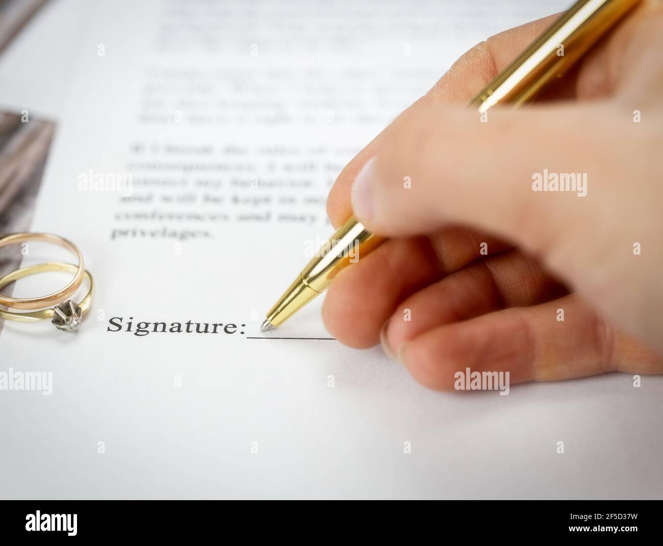 Marriage contract with two golden wedding rings and gold pen, prenuptial agreement, macro close up, sign with signanture,document,agreement concept Stock Photo