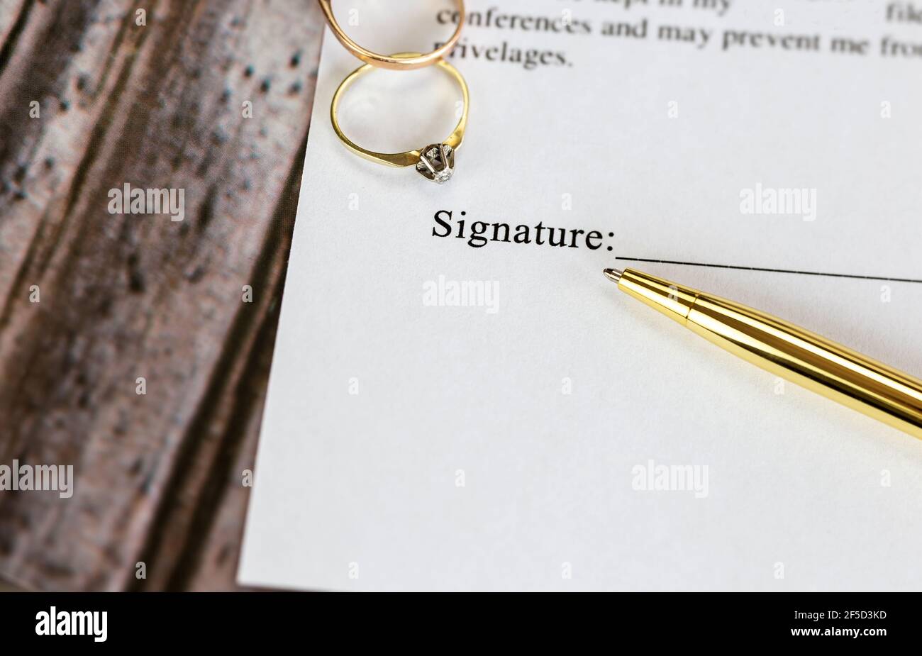 Marriage contract with two golden wedding rings and gold pen, prenuptial agreement, macro close up, sign with signanture,document,agreement concept Stock Photo