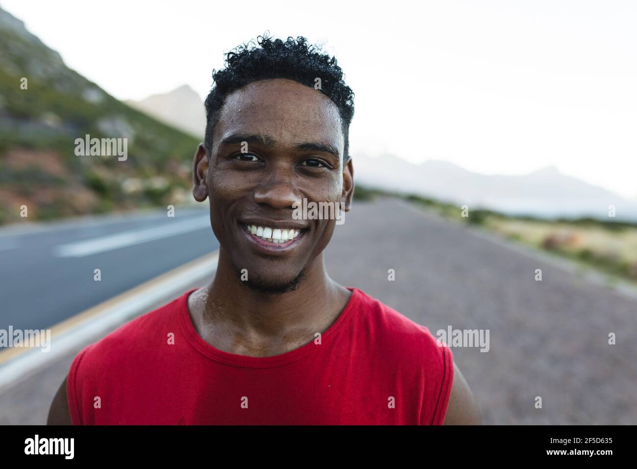 Portrait of fit african american man exercising outdoors on a coastal road smiling to camera Stock Photo