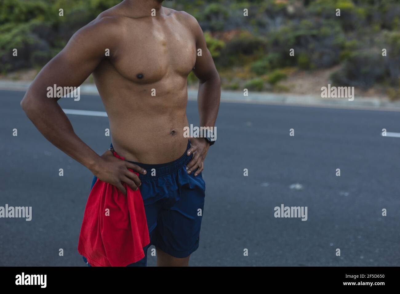 Midsection of fit african american man exercising outdoors on a coastal road Stock Photo
