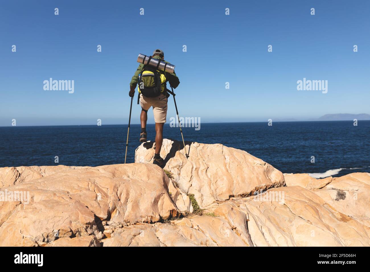 African american man exercising outdoors hiking using walking poles in countryside on a mountain Stock Photo