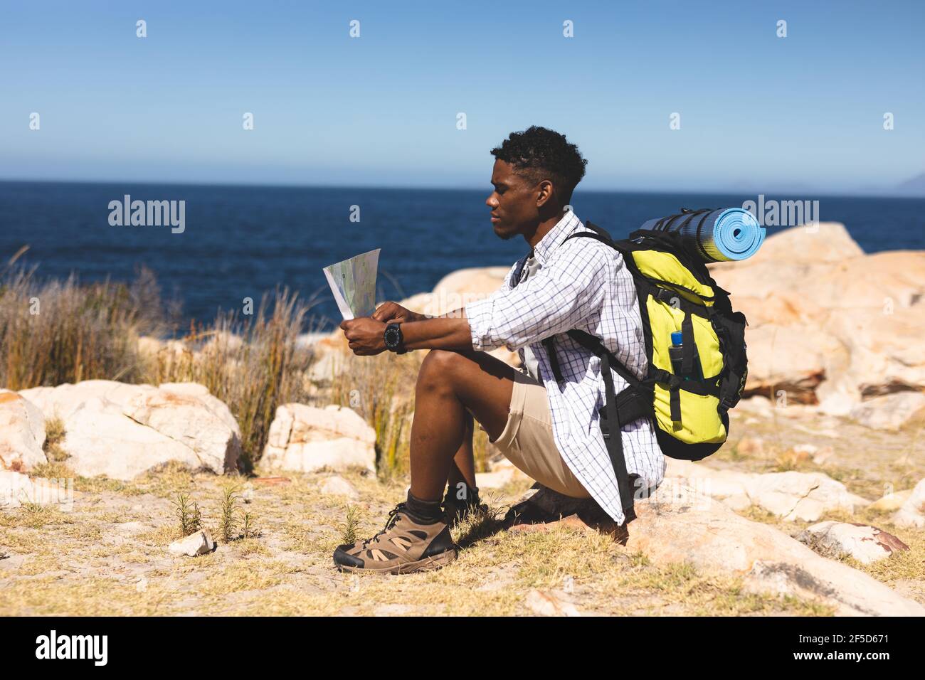 African american man exercising outdoors reading map in countryside on a mountain Stock Photo