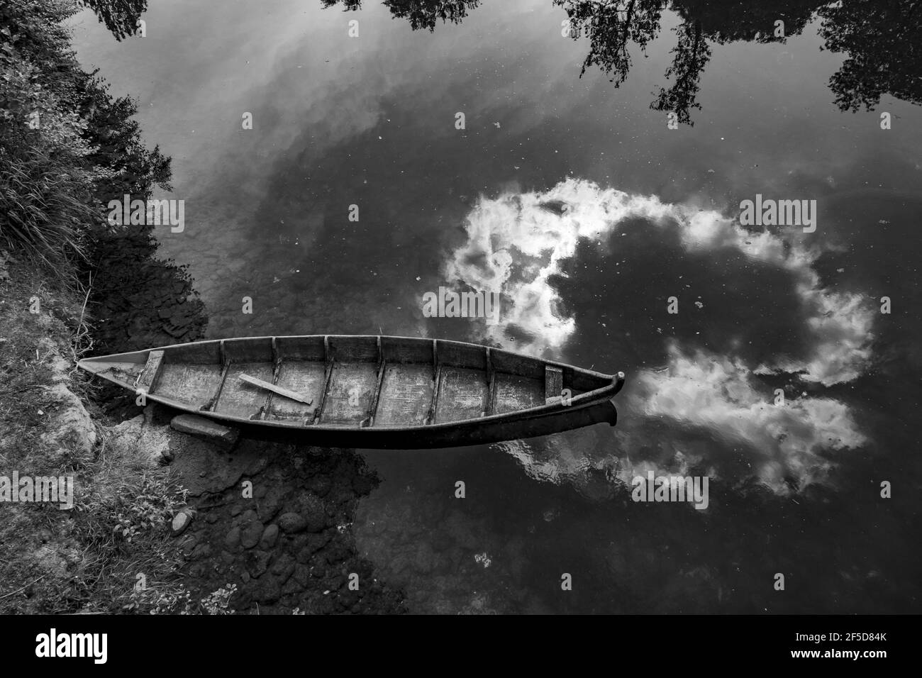 Top view of an old wooden boat moored on the lakeside in grayscale ...