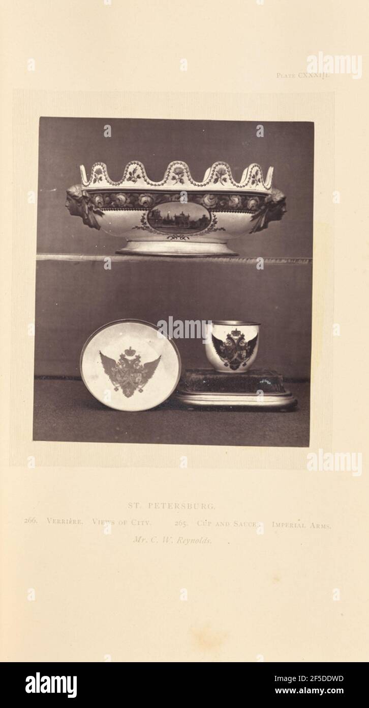 Verrière. A verriere on a shelf above a cup and saucer. The verriere has a scalloped edge and handles in the shape of faces in relief. It is painted with a cityscape in an oval medallion, along with flowers and a floral border. The cup and saucer are both decorated with painted imperial arms of Paul I of Russia.. (Recto, mount) upper right, printed in black ink: 'PLATE CXXXIII.' Lower center, printed in black ink: 'ST. PETERSBURG. / 266. VERRI»RE. VIEWS OF CITY. 265. CUP AND SAUCER. IMPERIAL ARMS. / Mr. C. W. Reynolds. italicized' Stock Photo