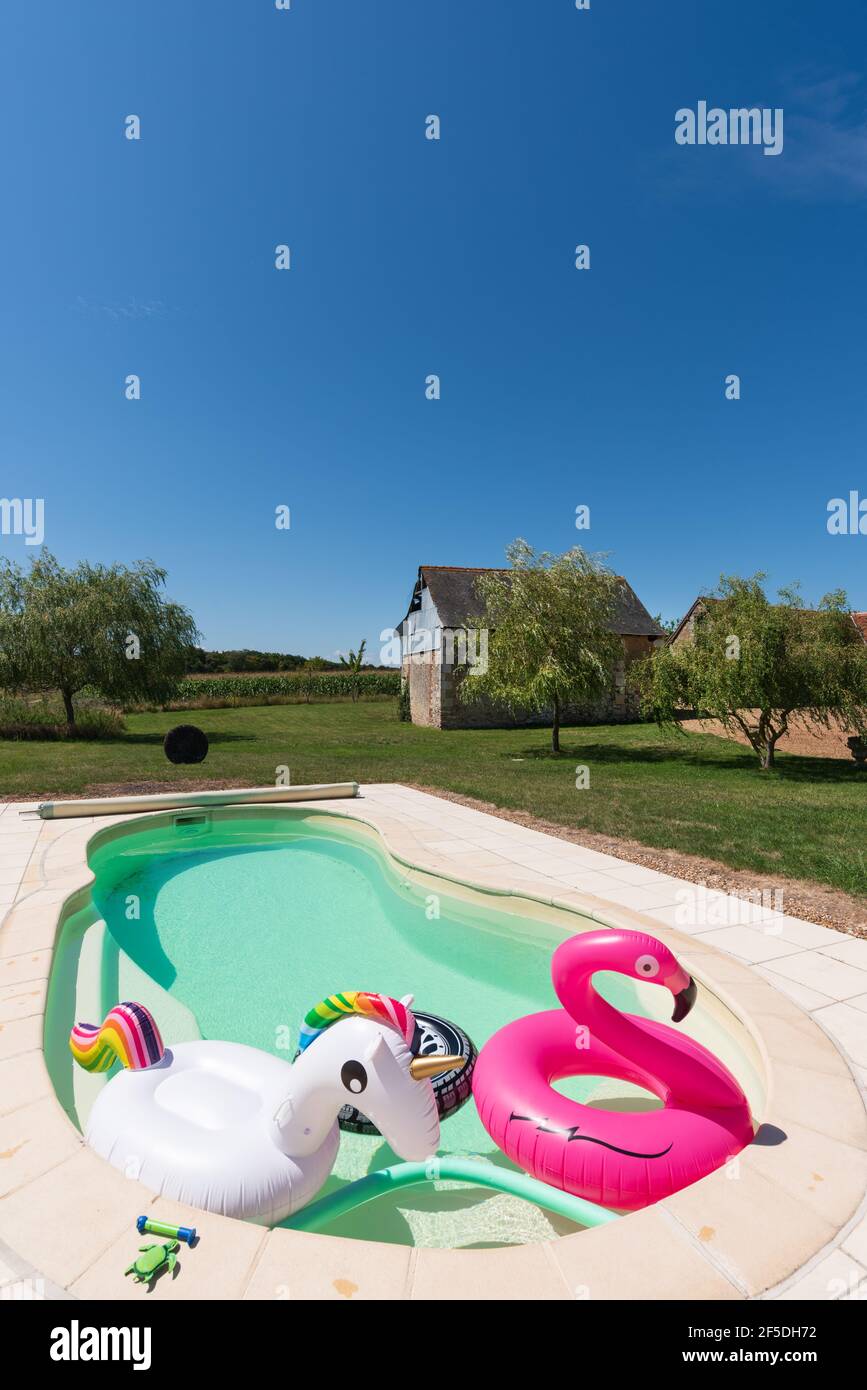 Pool toys in an outdoor pool under a bright blue sky. Stock Photo