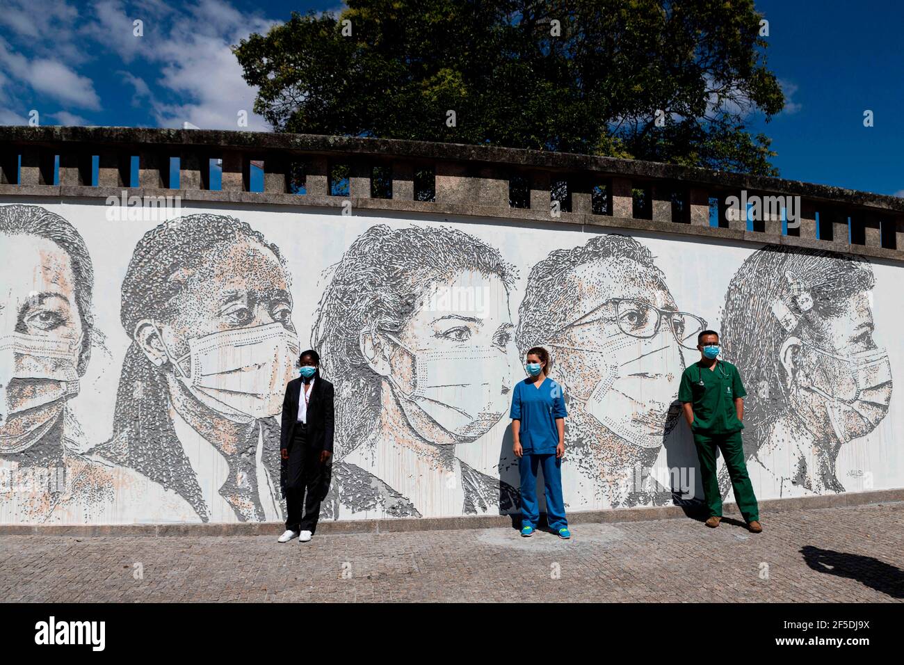 Porto, Portugal. 19th June, 2020. From left to right, Cristina Teixeira, receptionist, PatrÃ-cia Botelho, nurse and David Andrade, doctor next to the mural 'Linha da Frente: Projeto Scratching the Surface'', meaning ''Frontline: Project Scratching the Surface'' paying tribute to all the hospital staff in the frontline. Not only doctors and nurses but also janitors and receptionists by Vhils, a famous Portuguese street artist.The street murals are located at the Hospital de SÃ£o JoÃ£o, one of the biggest hospitals in Portugal and the main one to take care of COVID-19 patients in the northern Stock Photo