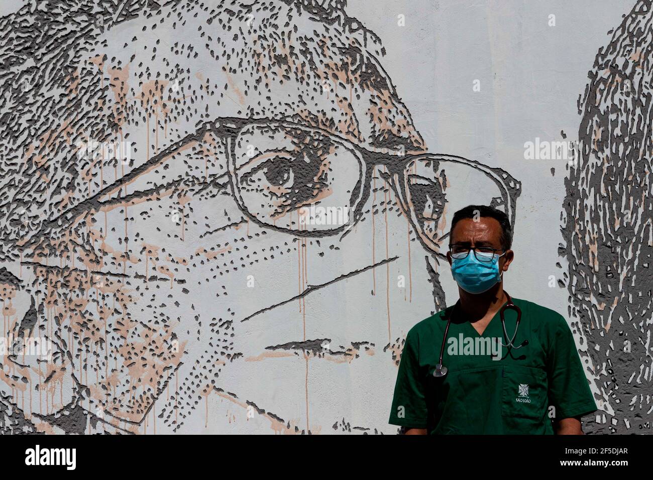 Porto, Portugal. 19th June, 2020. David Andrade, doctor poses in front of his portrait by Vhils, a famous Portuguese street artist, who created the mural 'Linha da Frente: Projeto Scratching the Surface'', meaning ''Frontline: Project Scratching the Surface'' paying tribute to all the hospital staff in the frontline. Not only doctors and nurses but also janitors and receptionists.The street murals are located at the Hospital de SÃ£o JoÃ£o, one of the biggest hospitals in Portugal and the main one to take care of COVID-19 patients in the northern part of the country. (Credit Image: © Teresa N Stock Photo