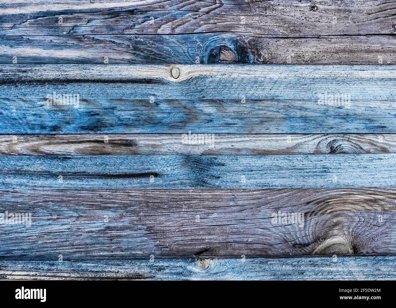 Dark gray texture of an old wooden fence with blue paint, abstract plank background. Stock Photo