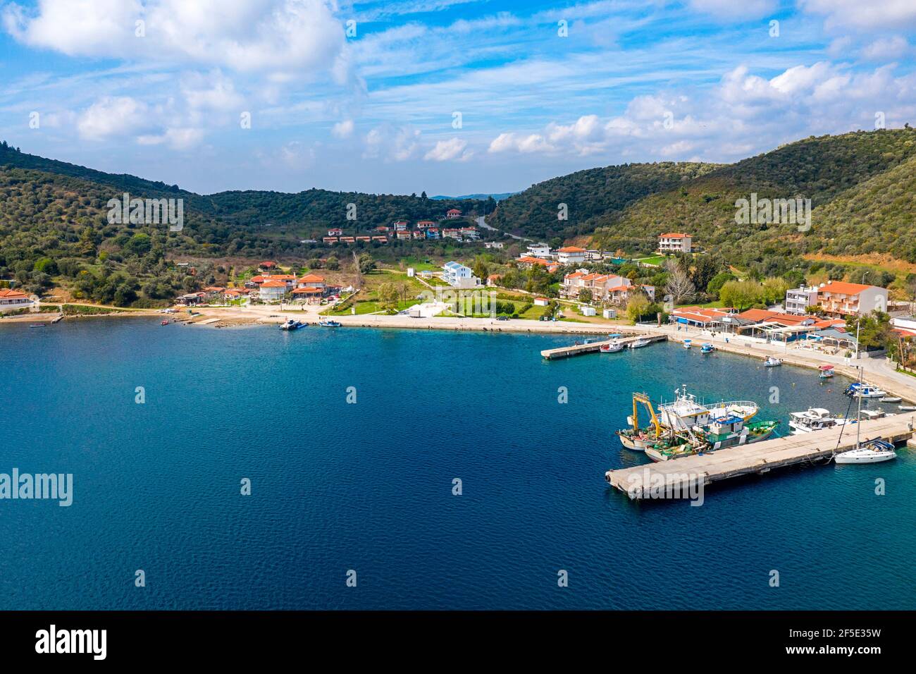 European country village on Mediterranean sea shore with coastline pier for fishing boats. Small resort town on green tree mountains summer background Stock Photo