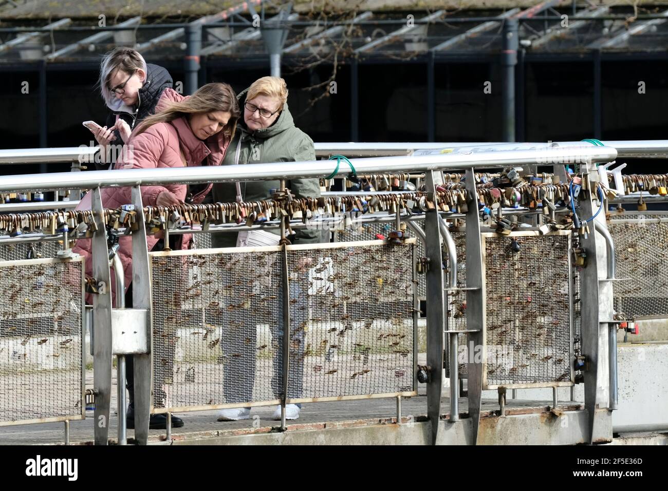 Bristol, UK. 26th Mar, 2021. People are out in the spring sunshine in Bristol despite Covid lockdown and recent protests. Two ladies checking the lovelocks on Pero's bridge in the sun. Credit: JMF News/Alamy Live News Stock Photo