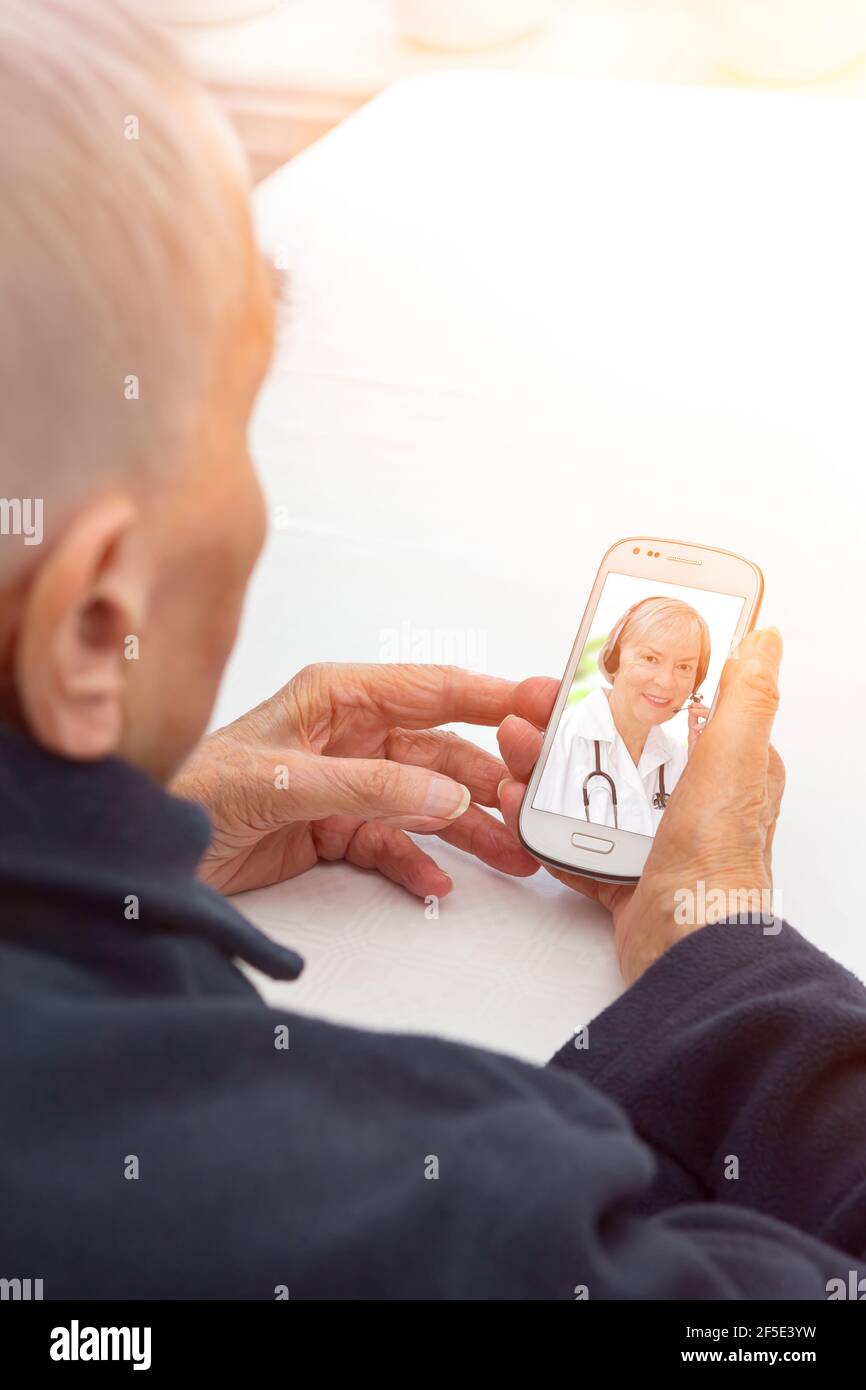 Telehealth or telemedicine concept: senior patient with headset making a video call with her doctor. Stock Photo