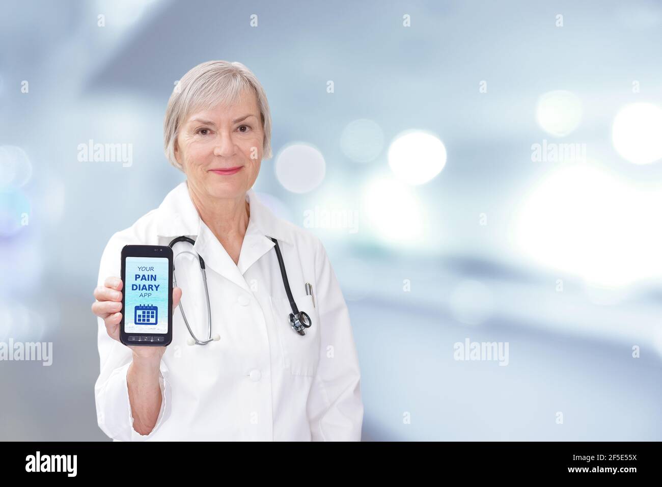 Friendly senior doctor showing a mobile or cell phone with a pain diary app. Stock Photo