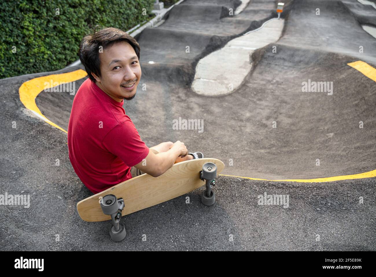 Asian man sitting with surfskate or skate board in pumptrack skate Park  when sunrise time over photo blur of pumptrack curve, extream sport,  healthy a Stock Photo - Alamy