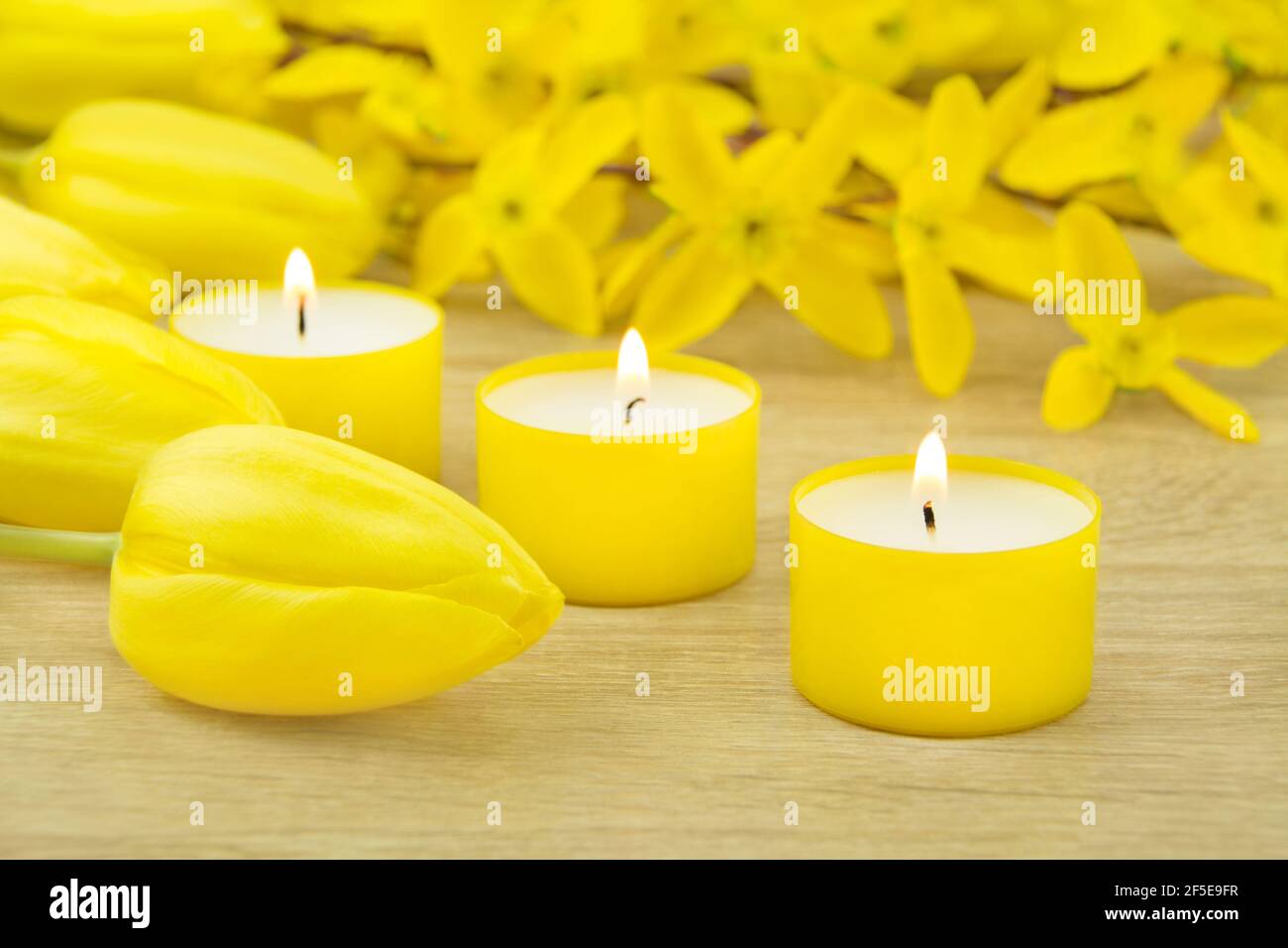 Gelbe Kerzen und Tulpen auf Holz Stock Photo
