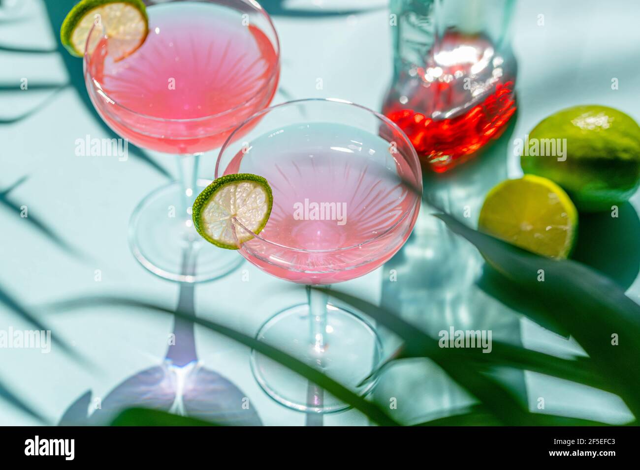 A cocktail in a glass with red chilly pepper and a cutting board with pepper, ginger ingredients  at the background. Stock Photo
