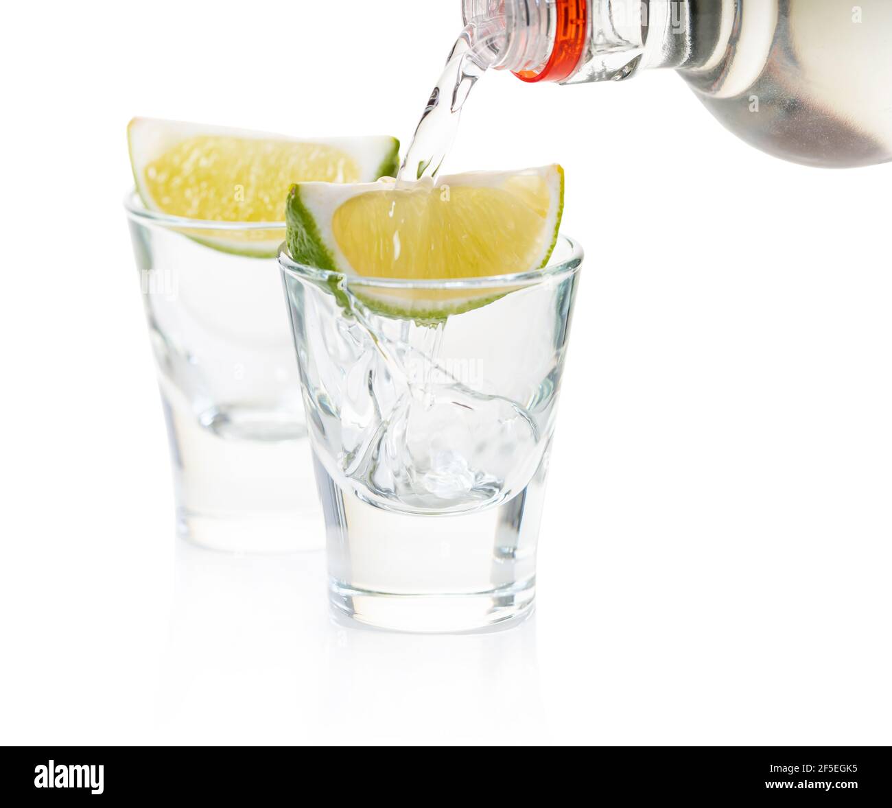 strong alcohol pouring into shot glasses on white background Stock