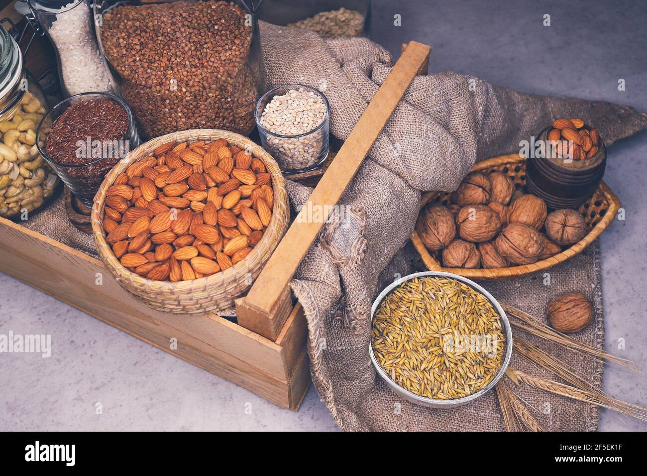 Variety of cereals and nuts on table. Walnuts, almonds, wheat grains and  ears of corn in cans and baskets. Alternative sources of protein and  vitamins Stock Photo - Alamy