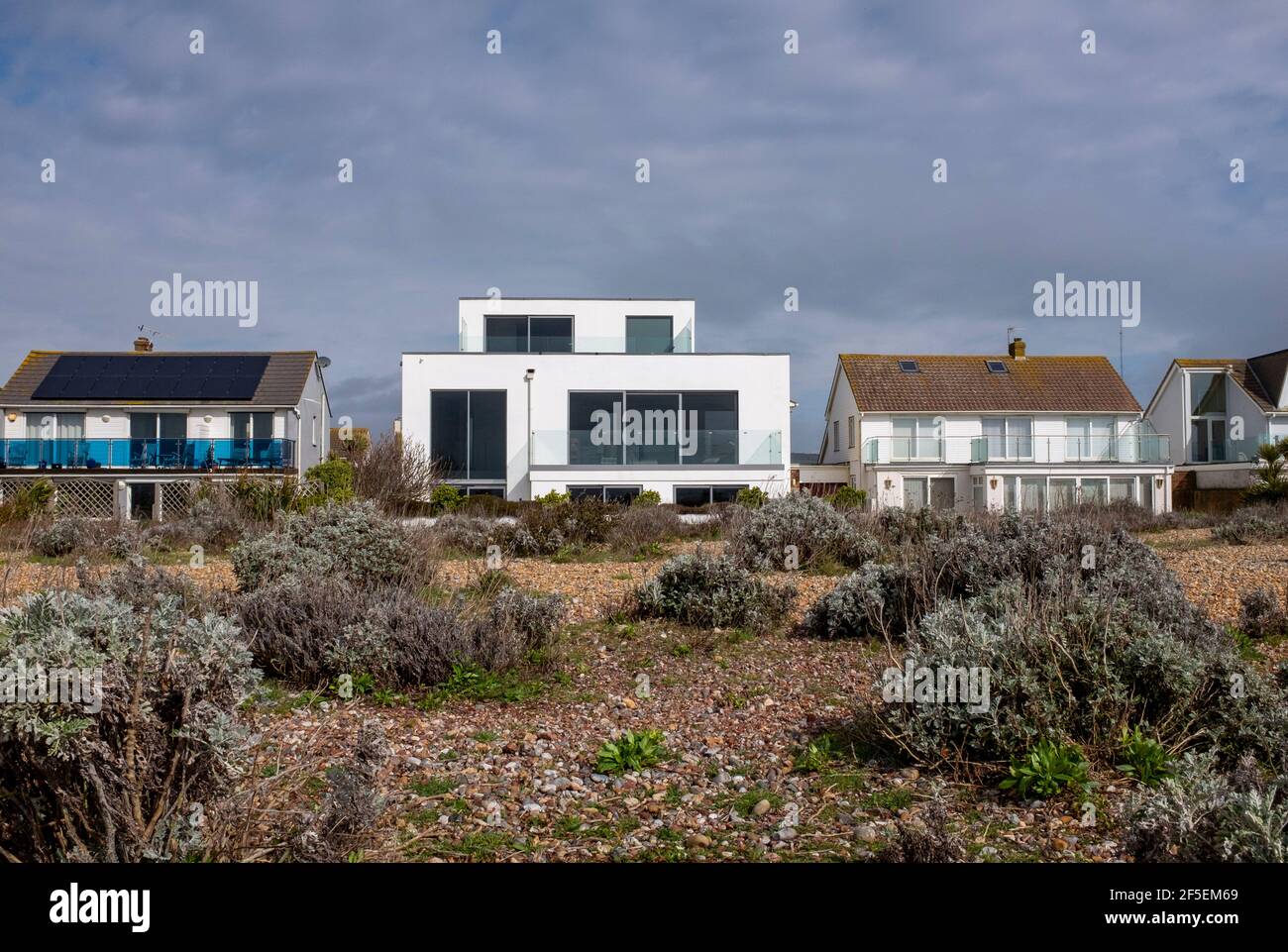 Beach house on Shoreham Beach overlooking the sea with rare vegetation growing on the shingle including kale and yellow horned poppies Stock Photo