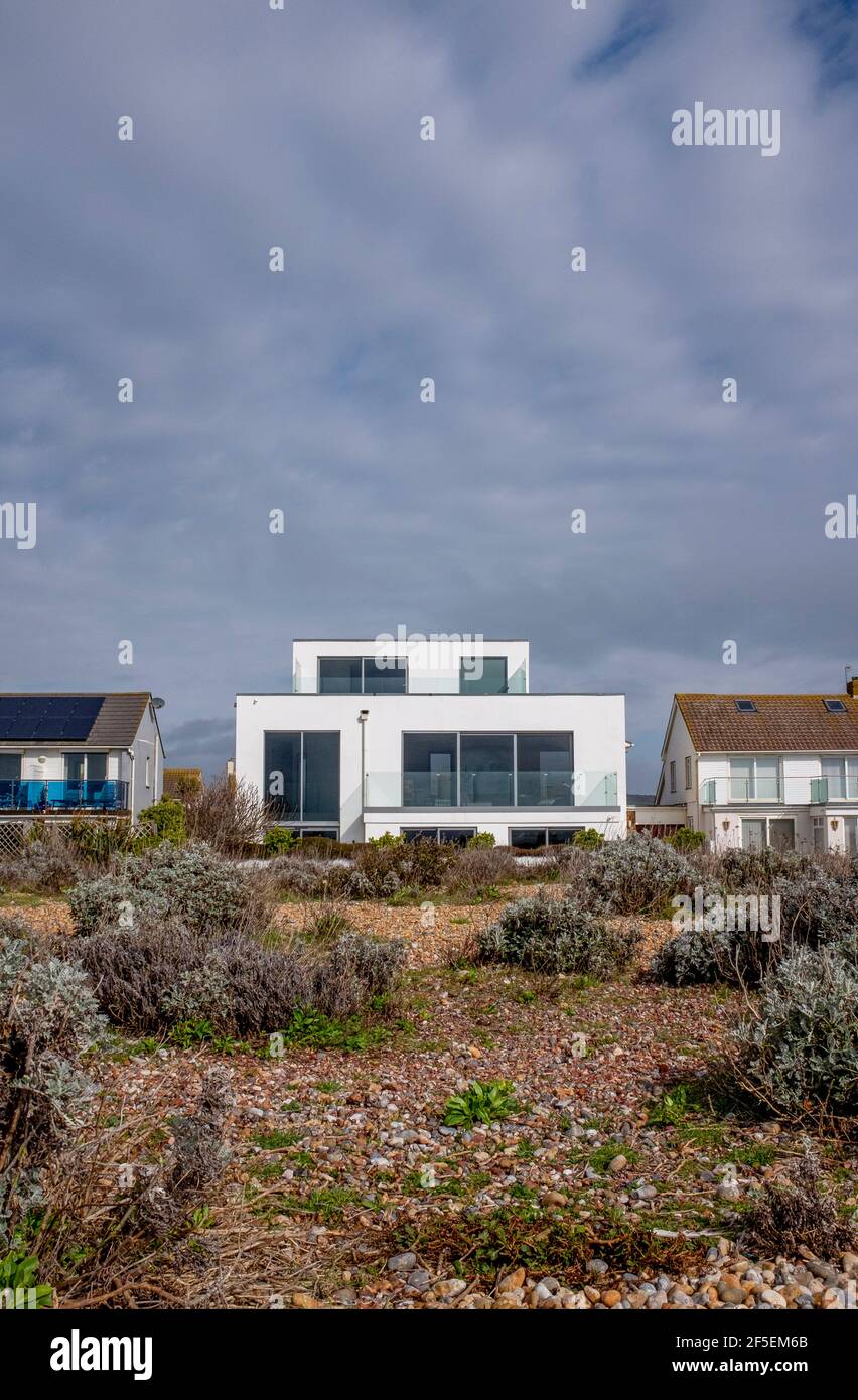 Beach house on Shoreham Beach overlooking the sea with rare vegetation growing on the shingle including kale and yellow horned poppies Stock Photo