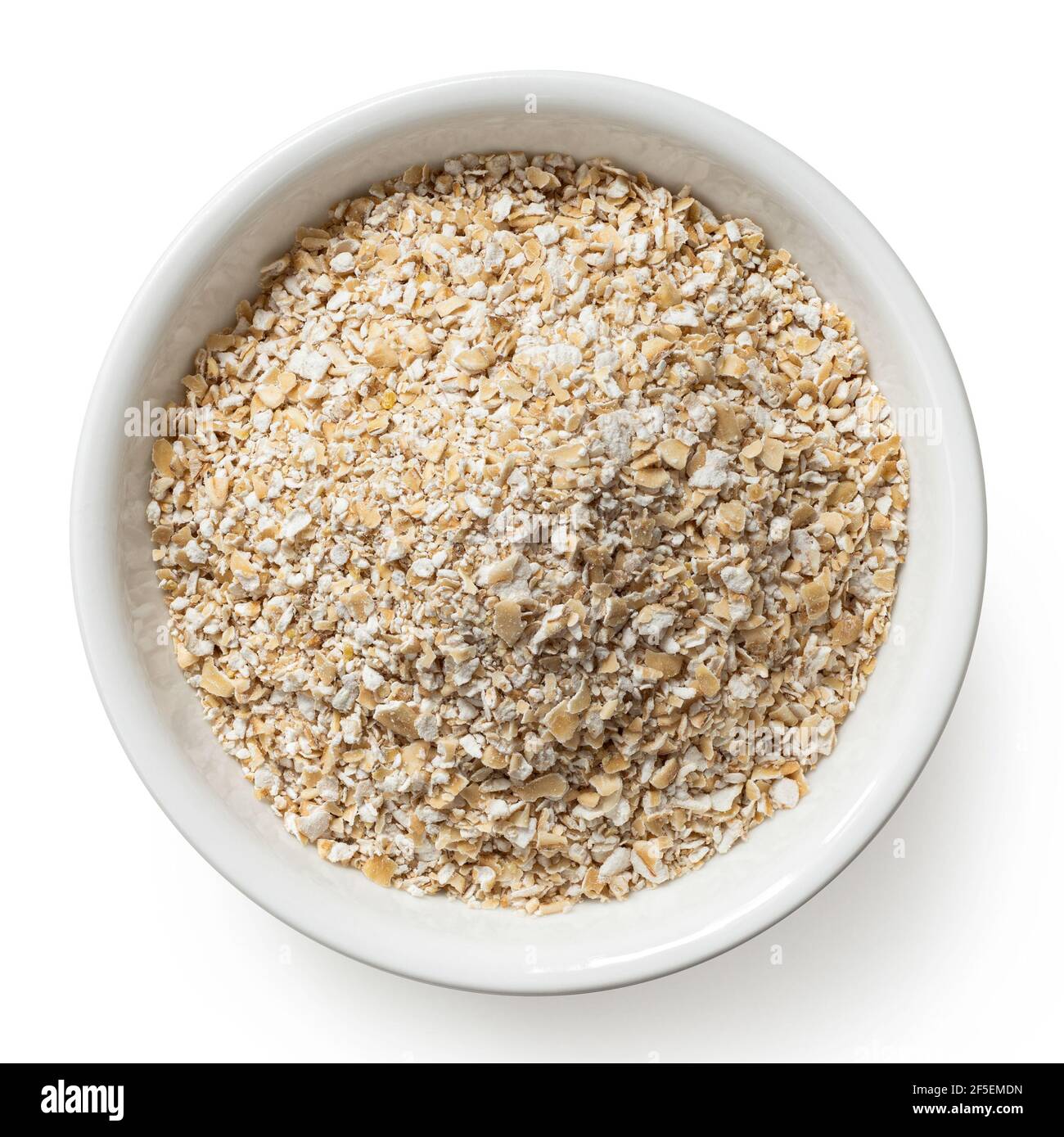 Uncooked coarse oatmeal in a white ceramic bowl isolated on white. Top view. Stock Photo
