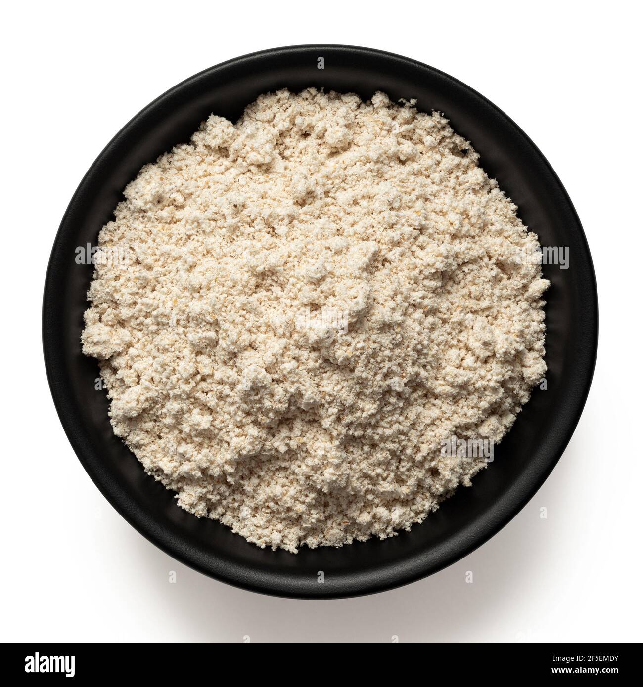 Oat flour in a black ceramic bowl isolated on white. Top view. Stock Photo