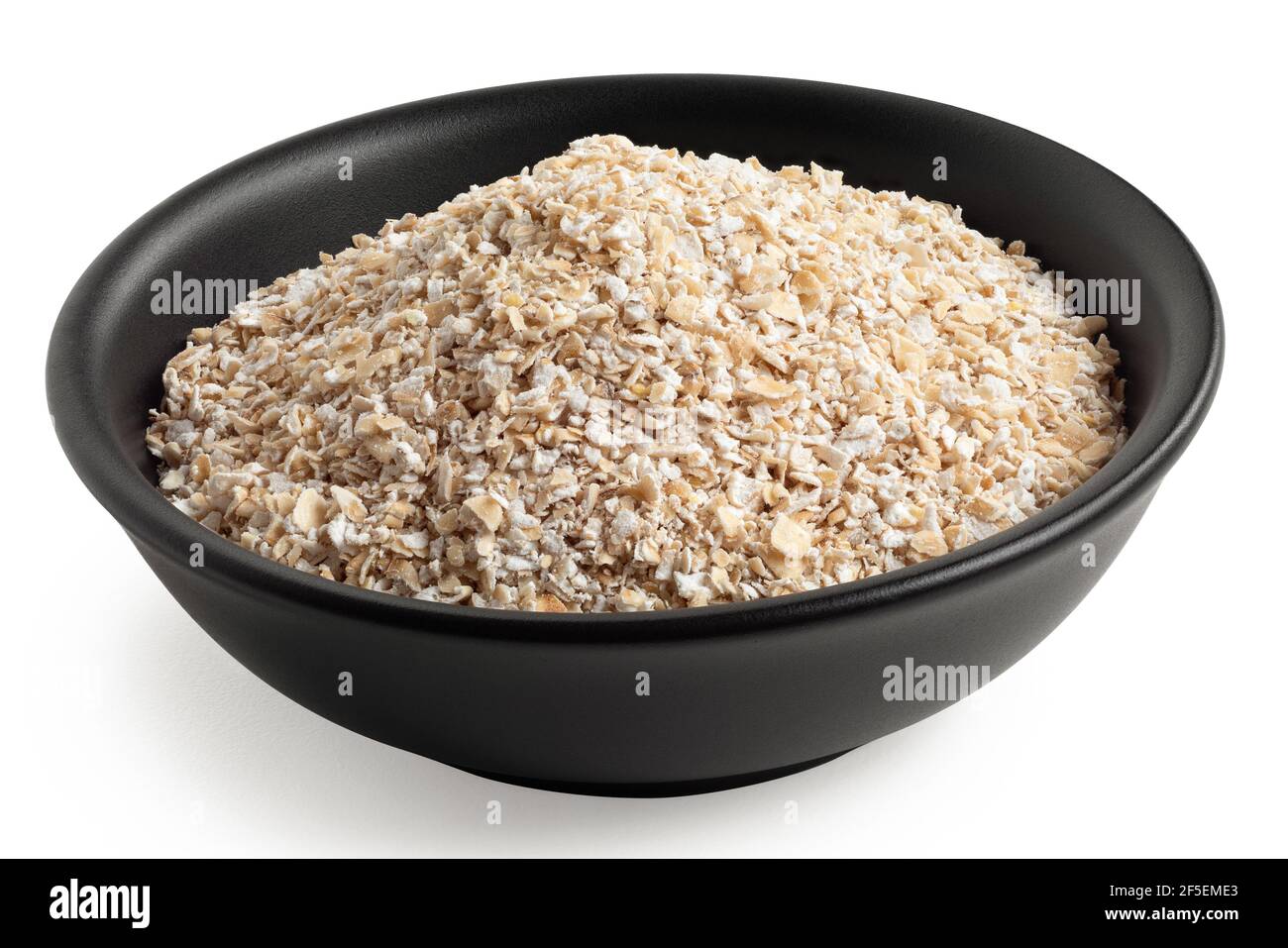 Uncooked coarse oatmeal in a black ceramic bowl isolated on white. Stock Photo