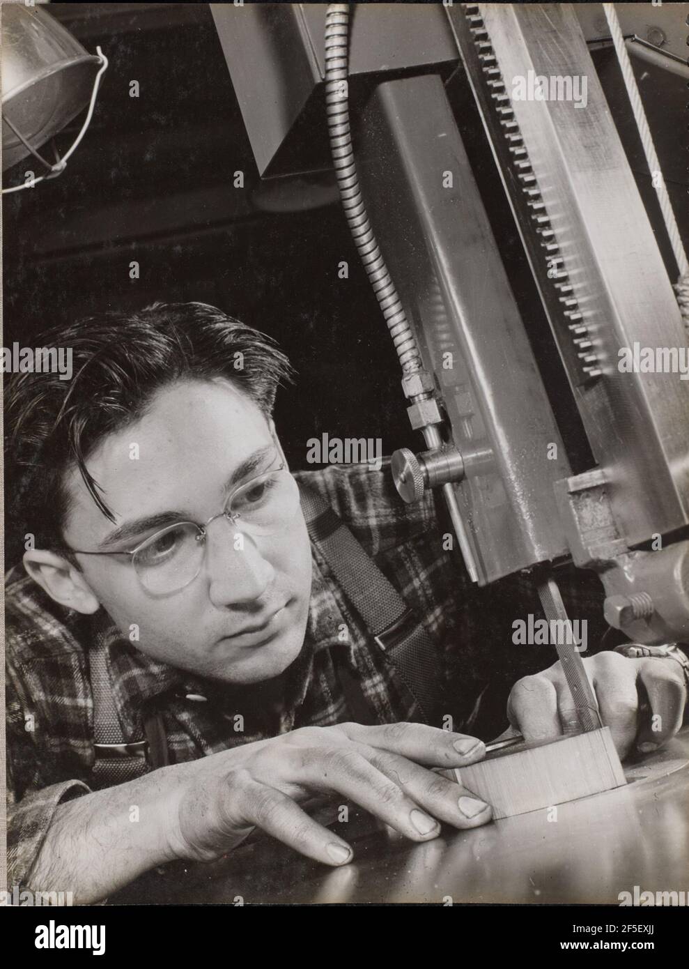 Man wearing glasses works intently with an industrial file. Arnold Eagle (American, 1909 - 1992) Stock Photo