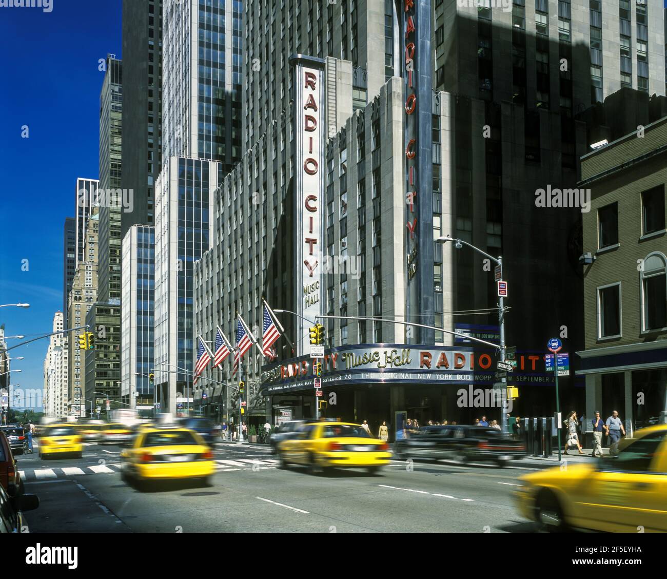 2002 HISTORICAL YELLOW TAXI CABS (©FORD MOTOR CO 2000) RADIO CITY MUSIC HALL (©EDWARD DURREL STONE 1932) SIXTH AVENUE MANHATTAN NEW YORK CITY USA Stock Photo
