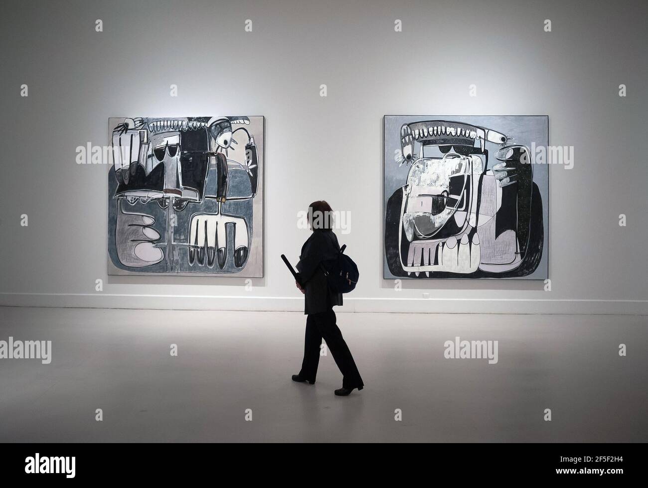 A journalist seen walking in front of the large paintings during 