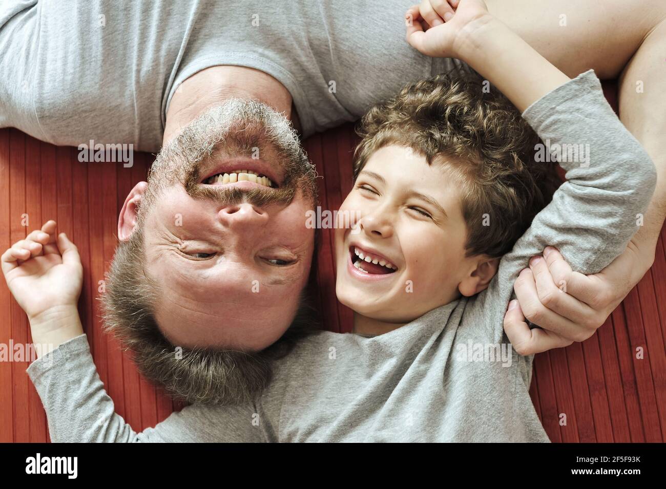 Father and son lie on the floor, hug, laugh, communicate with each other with pleasure. Stock Photo