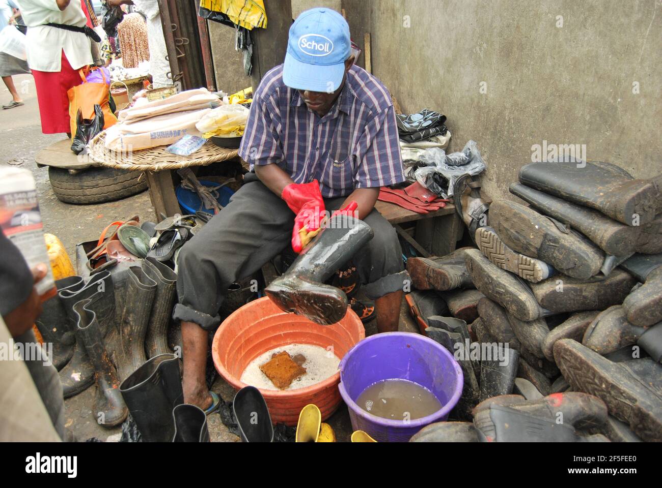 Man washing his rain boots for renting during the rainy season in Mile 12 Stock Photo